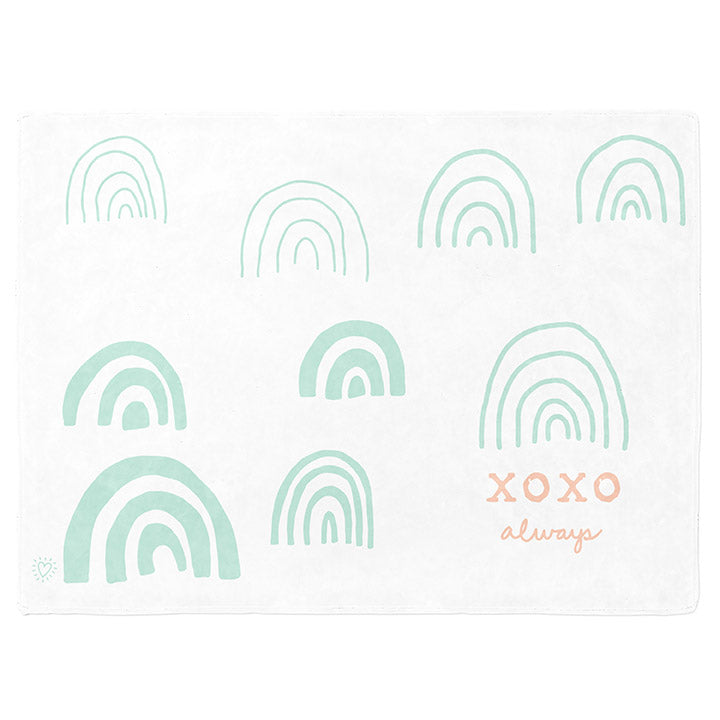 50 by 60 inch silky-soft fleece blanket that is hypoallergenic. Perfect size for an adult. Bright white blanket printed on one side only. 9 hand drawn mint green rainbows in varying sizes scattered across blanket. The words xoxo, always in peach typewriter font sits under one rainbow. A small Adoptionly Yours heart logo by itself in mint green in lower left corner of blanket on front. 