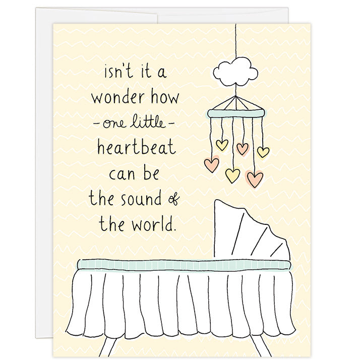 4.25 x 5.5 inch greeting card. Blank inside. Simple and charming illustration style. Title Isn’t it a wonder how one little heartbeat can be the sound of the word. Drawing of a white basinet with a mobile hanging above with peach and yellow hearts.
