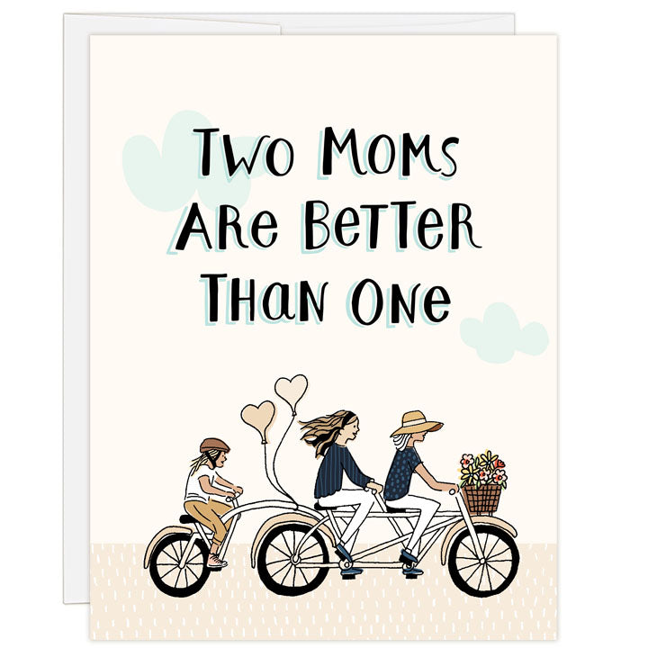 Illustrated Mother's Day card with line and ink drawing of two moms riding a tandem bicycle with a child riding on back, balloons and flowers in basket, puffs of clouds in the sky. Hand-drawn text: TWO MOMS ARE BETTER THAN ONE. Inside message: Happy Mothers' Day.