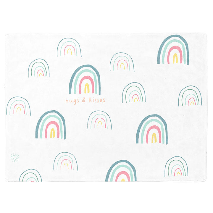 30 by 40 inch silky-soft fleece blanket that is hypoallergenic. Perfect size for a toddler or child. Bright white blanket printed on one side only. 15 large and small hand drawn rainbows scattered across blanket in magenta, light teal, bright yellow and green with the words hugs & kisses hand drawn in peach color. Adoptionly Yours heart logo by itself in light teal in lower left corner of blanket on front. 