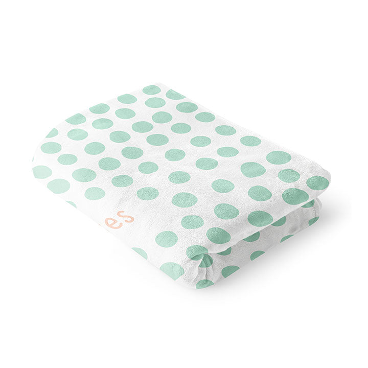 Folded 50 by 60 inch silky-soft fleece blanket that is hypoallergenic. Perfect size for a toddler or child. Bright white blanket printed on one side only. 4 inch hand drawn dots scattered across blanket in mint green with the words hugs & kisses hand drawn in a peach color. The words adoptionly yours in mint green typewriter font on lower left corner of blanket on front. 