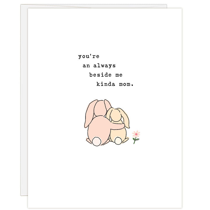 Illustrated line and ink Mother's Day card with a pink mother bunny's arm around a smaller cream bunny sitting next a flower as shown from behind. Text: you're an always beside me kinda mom.