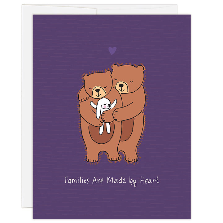 4.25 x 5.5 inch adoption greeting card. Blank inside. Simple and charming illustration style. Title Families Are Made by Heart. Main image is two brown bears with eyes closed and smiling while hugging a small white bunny rabbit with eyes closed and hugging bear back.