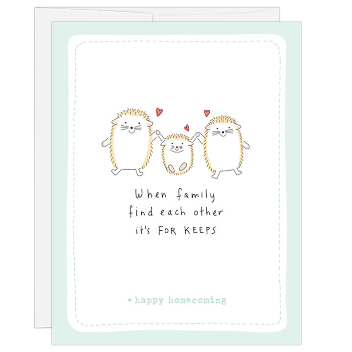 4.25 x 5.5 inch greeting card. Blank inside. Simple and charming illustration style. Title When family find each other it’s FOR KEEPS. Sub title *happy homecoming. Main image is two adult hedgehogs and one child hedgehog in center. They are holding hands and small red hearts above hedgehogs.