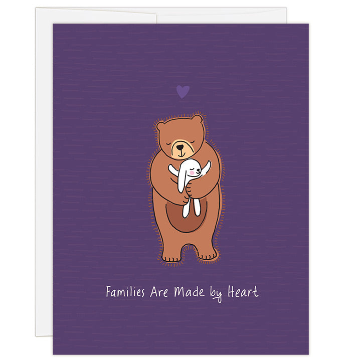 4.25 x 5.5 inch greeting card. Blank inside. Simple and charming illustration style. Title Families Are Made by Heart. Main image is one brown bear with eyes closed and smiling while hugging a small white bunny rabbit with smile and eyes closed hugging bear back.
