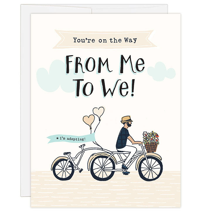 4.25 x 5.5 inch greeting card. Blank inside. Simple illustration style. Title You’re on the Way From Me to We! Sub title *i’m adopting! Main image is man on tandem bicycle with flowers in basket and balloons on back. Back seat is empty.