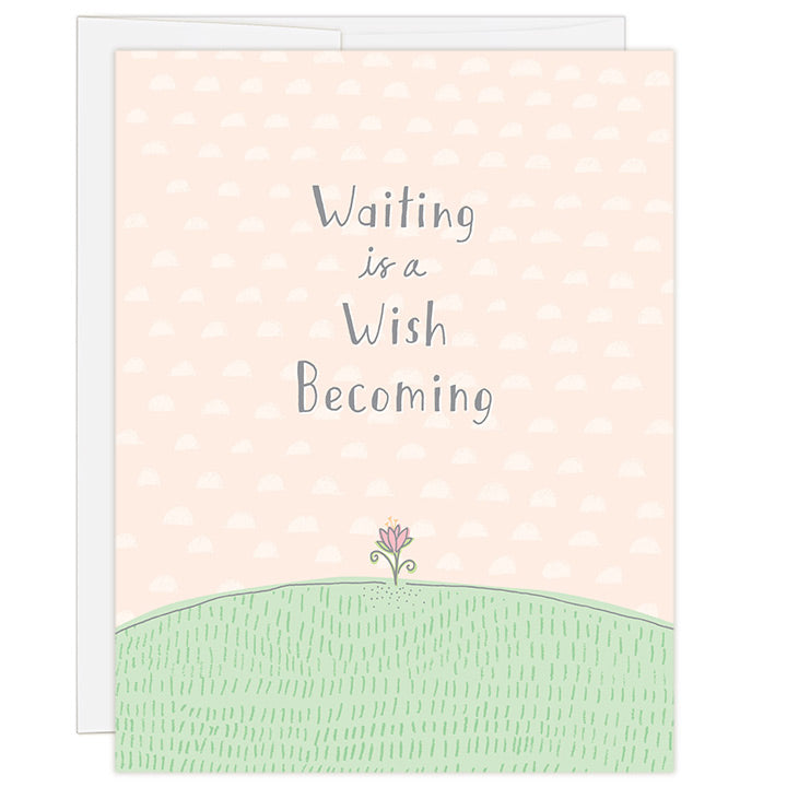 4.25 x 5.5 inch greeting card. Blank inside. Simple and charming illustration style. Title Waiting is a Wish Becoming. Main image is a small hand drawn pink flower poking out of green grass. Background is light peach with a hand drawn pattern of small half moons. Adoption greeting card for encouraging an adopting family along the wait for a child.
