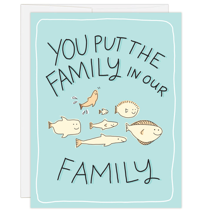 4.25 x 5.5 inch greeting card. Blank inside. Cover art is simple line illustration of seven fish swimming together. Fish are different shapes and styles with one fish joyously splashing upward. Cream fish on a teal background. Text: you put the family in our family.