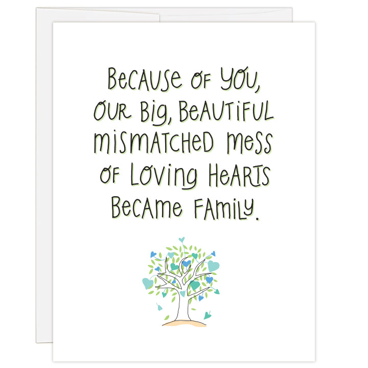 4.25 x 5.5 inch greeting card. Blank inside.  White cover background with line illustration of tree with different shaped and colored hearts in shades of blue. Large hand-illustrated text reads: Because of you, our big, beautiful mismatched mess of loving hearts became family.