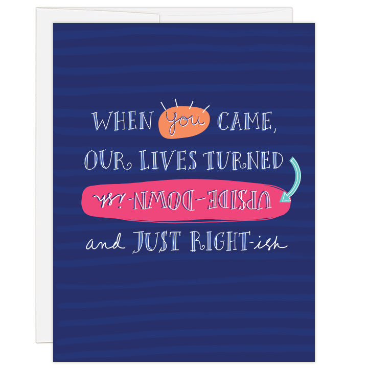 4.25 x 5.5 inch greeting card. Blank inside.  Cover background stripes in shades of blue with big white text selectively called out with colors reading: When you came our lives turned upside-down-ish and just right-ish.  
